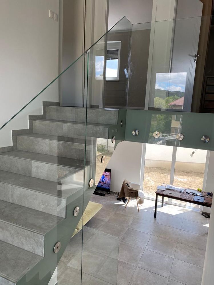 Glasbrüstung entlang einer Galerie im Obergeschoss, Treppenlauf dahinter