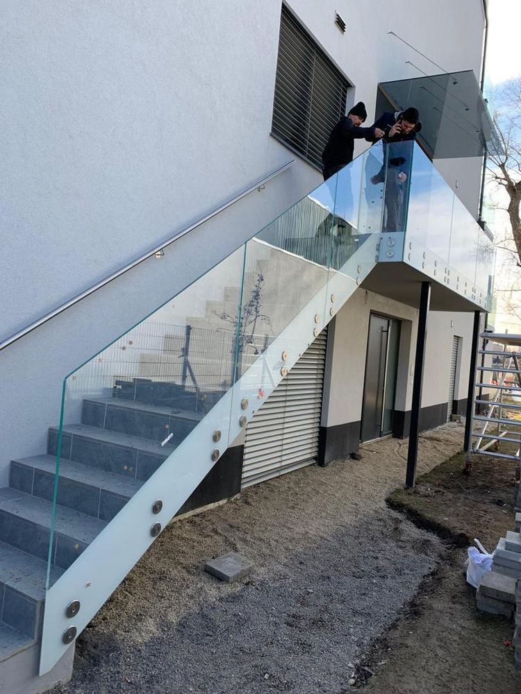 Monteur richtet das Glasgeländer einer Außentreppe aus