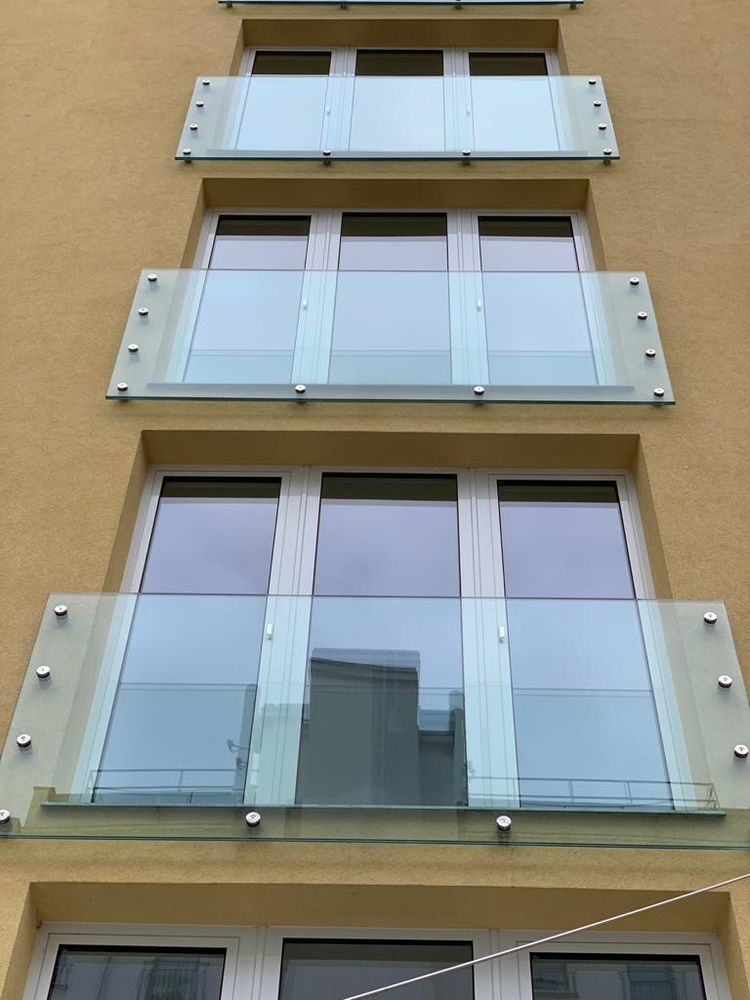 Französische Balkone aus Glas über mehrere Geschosse einer Hausfassade