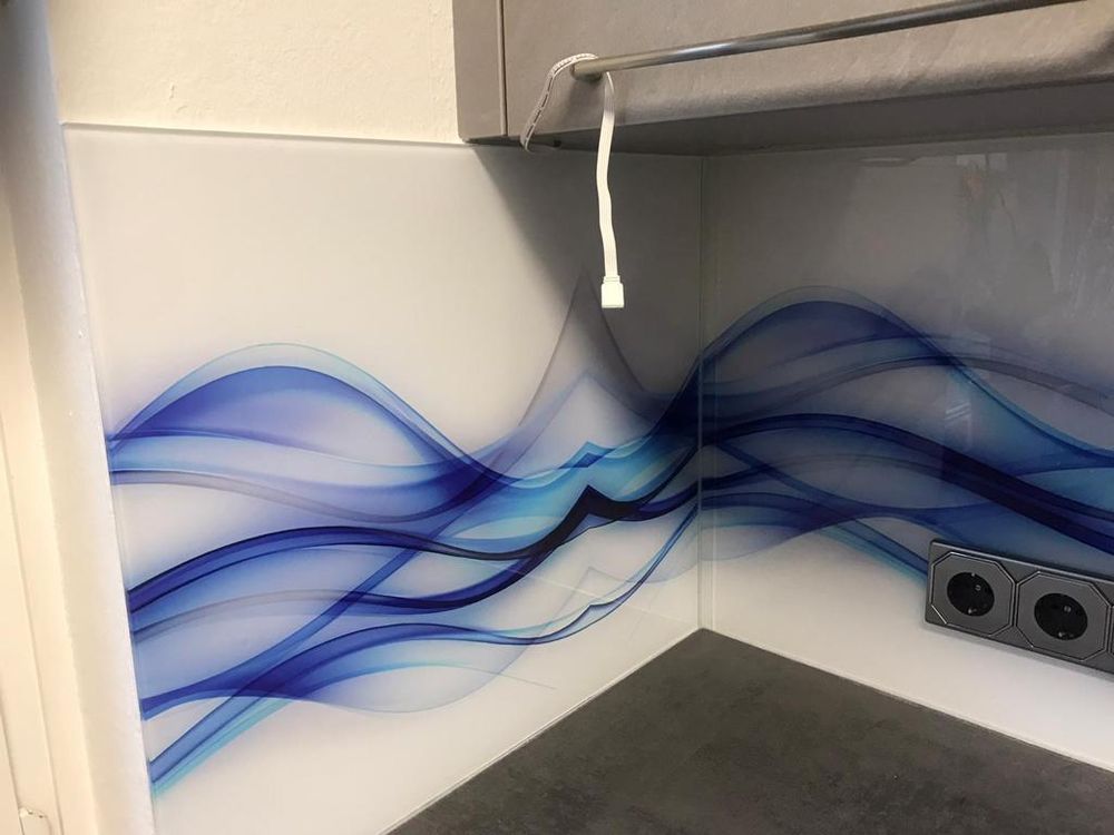 Über Eck geführte Glasrückwand mit blauem Wellenmotiv, Steckdosen sauber ausgeschnitten