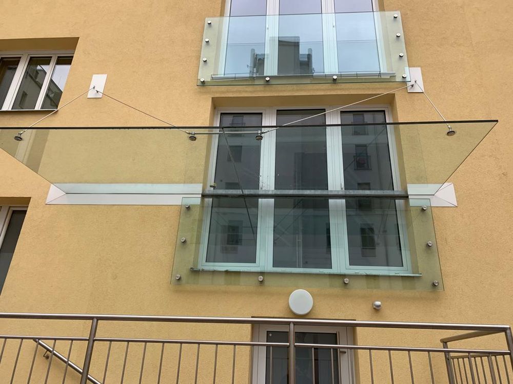 Glasvordach mit Edelstahl-Seilabhängung über einem Balkon
